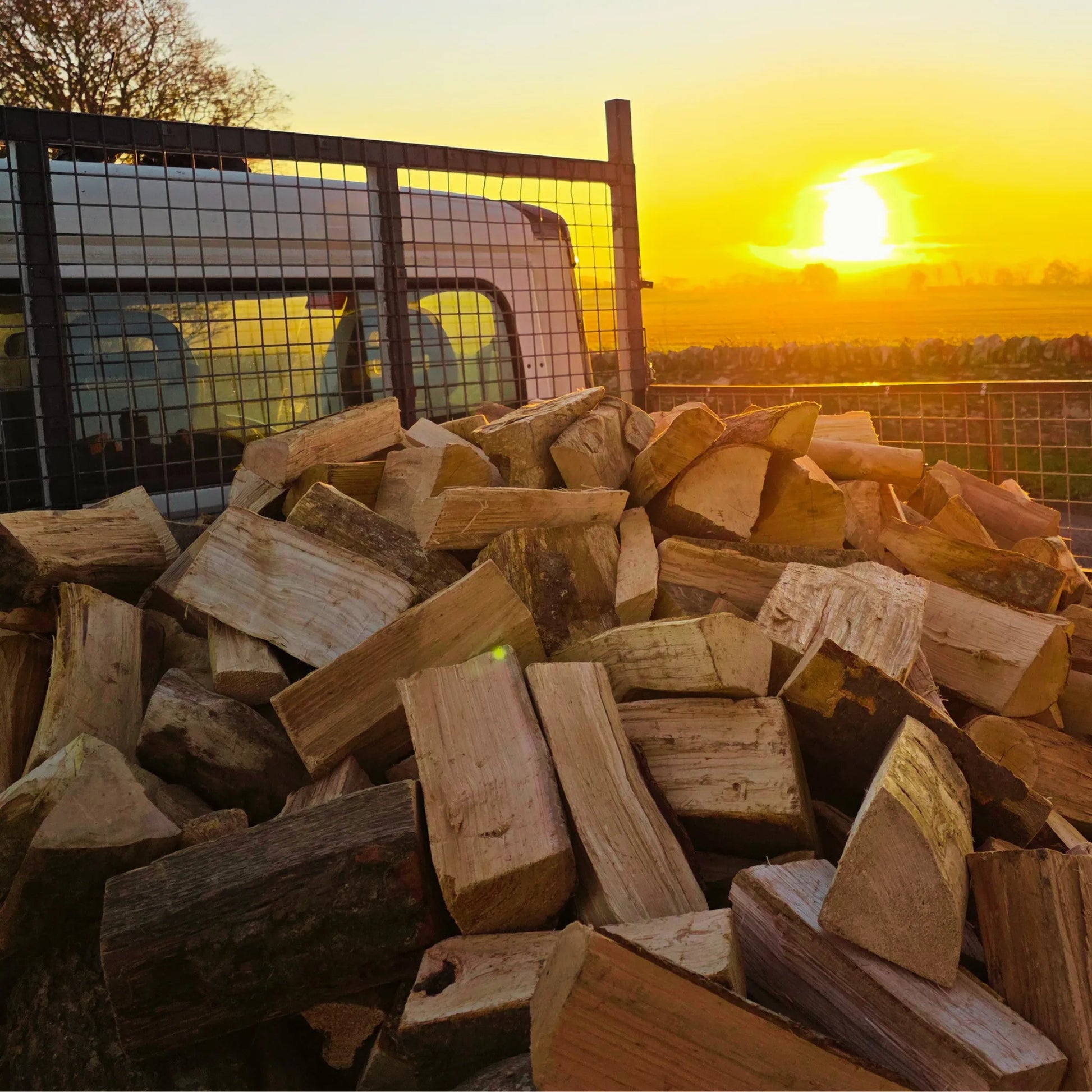 Stack of dry firewood sticks with a sunset in the background on way to a loose tipped log delivery in Arbroath, Angus.