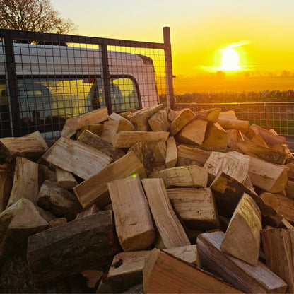 Stack of dry firewood sticks with a sunset in the background on way to a loose tipped log delivery in Arbroath, Angus.