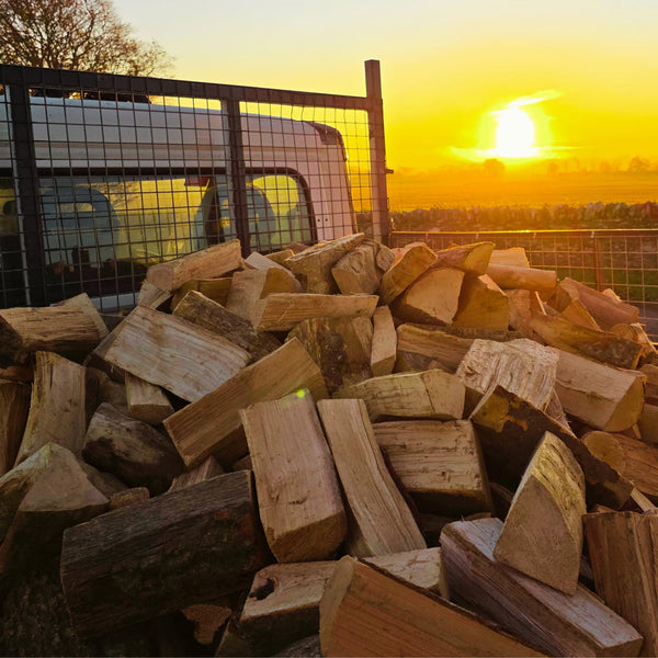 Stack of dry firewood sticks with a sunset in the background on way to a loose tipped log delivery in Arbroath, Angus.