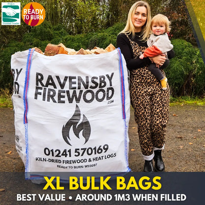 Woman holding a child next to an XL bulk bag of kiln-dried firewood logs with promotional text saying Ravensby Firewood.