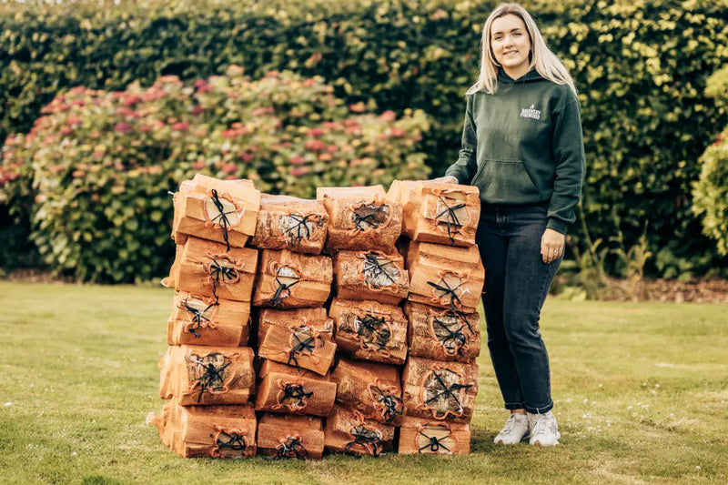 Woman standing next to a stack of kiln-dried firewood grab net bags of logs in Arbroath, Angus