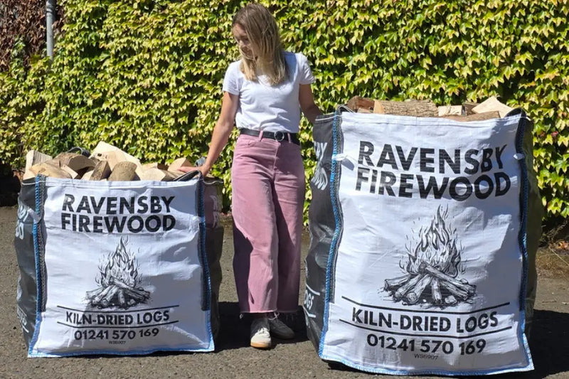 A woman stands next to two bulk bags containing kiln-dried logs in Angus
