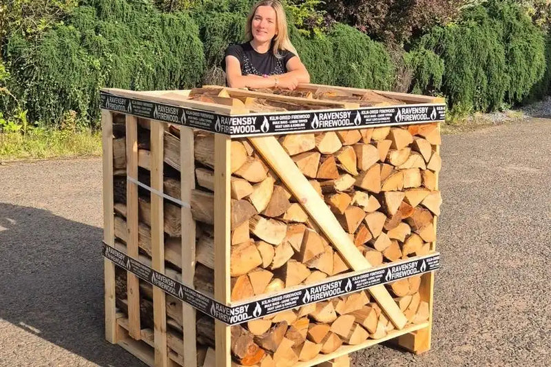 Woman standing behind a crate of kiln-dried ash firewood