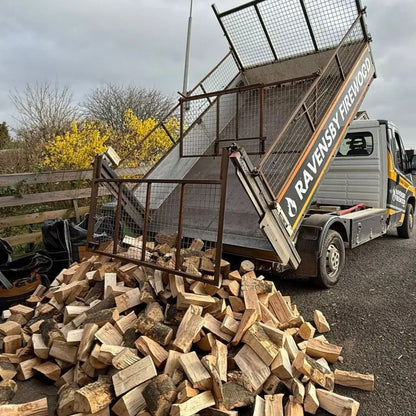 Truck loaded with kiln-dried firewood logs and 'Ravensby Firewood' branding tipping logs at a delivery in Arbroath, Angus.
