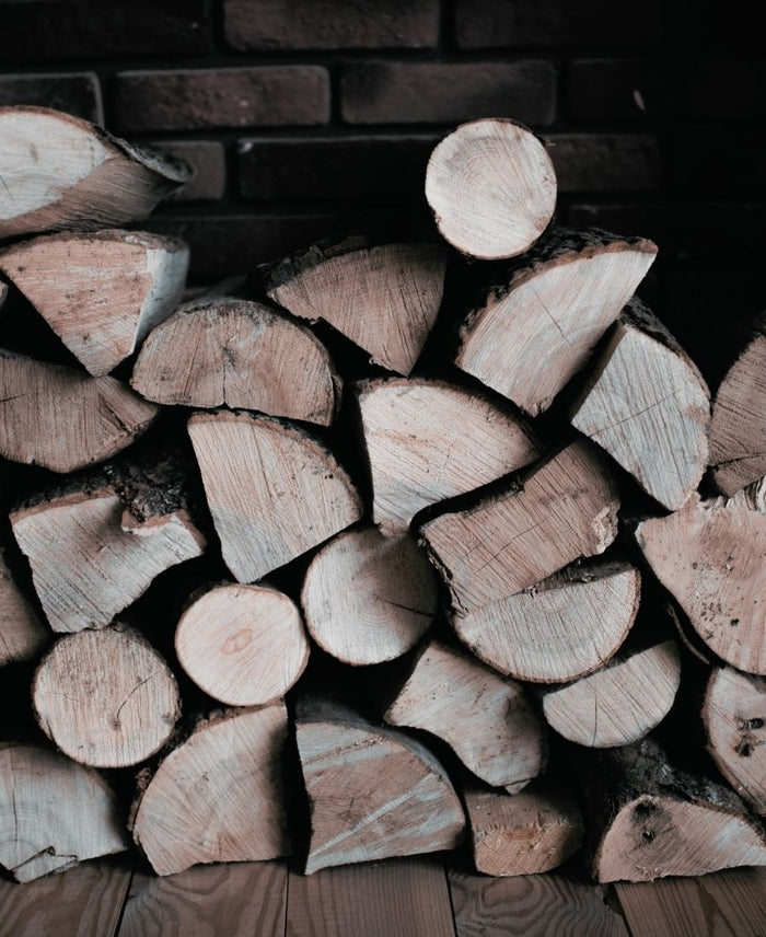 A stack of neatly packed firewood including ash, birch and oak logs