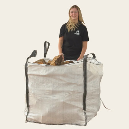 Woman standing next to a builders tonne bag of firewood logs in Dundee