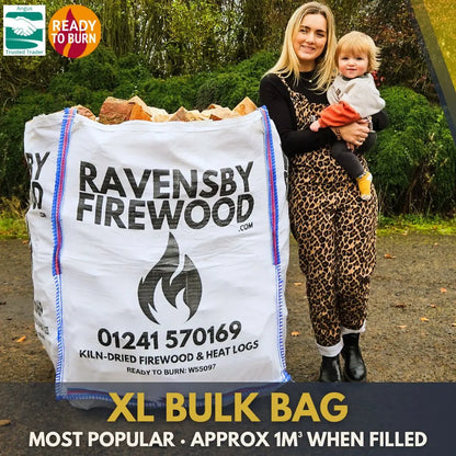 Woman holding a child next to an XL bulk bag of kiln-dried firewood logs with promotional text saying Ravensby Firewood.