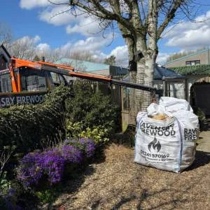 Bulk-Bag of hardwood logs being delivered with long reach crane into a garden